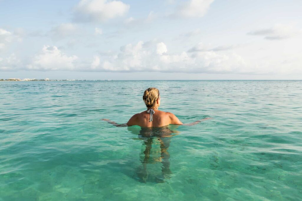 adult-woman-standing-in-ocean-water-at-sunset-PVRUYWU